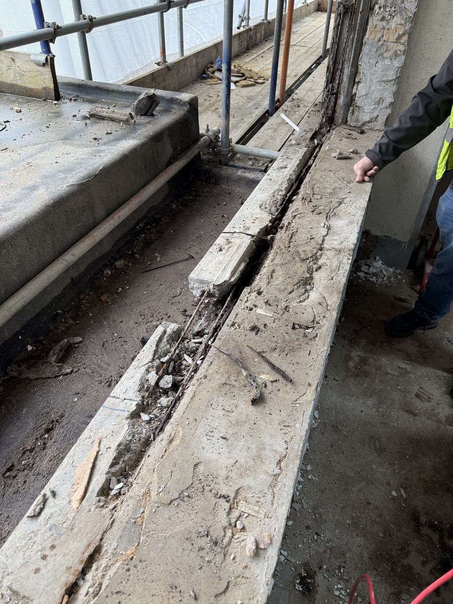 Spalled concrete with exposed, corroded reinforcement bar before repair, Guildford office conversion