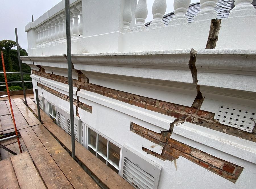 Severe stepped cracking through render and brickwork before masonry beam repair