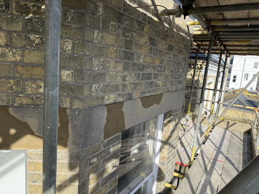 Spalling concrete lintel on a seafront block of flats in Brighton before repair